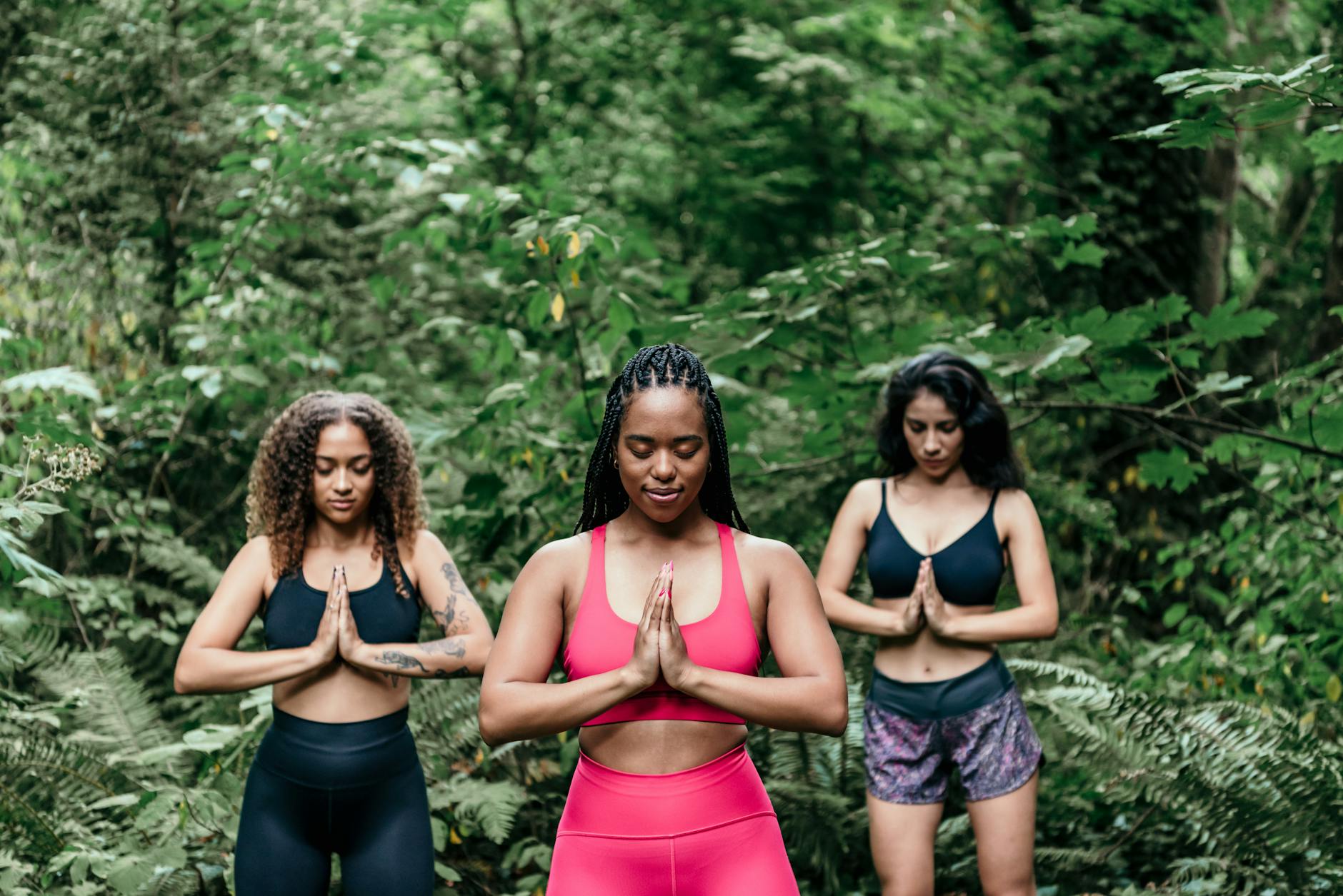 women wearing sports bra meditating in the woods