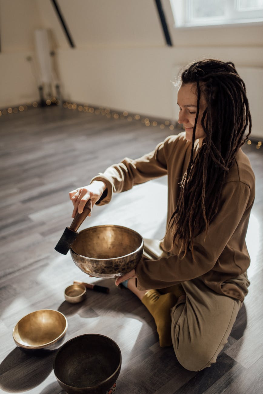 a woman in brown sweater holding a healing bowl