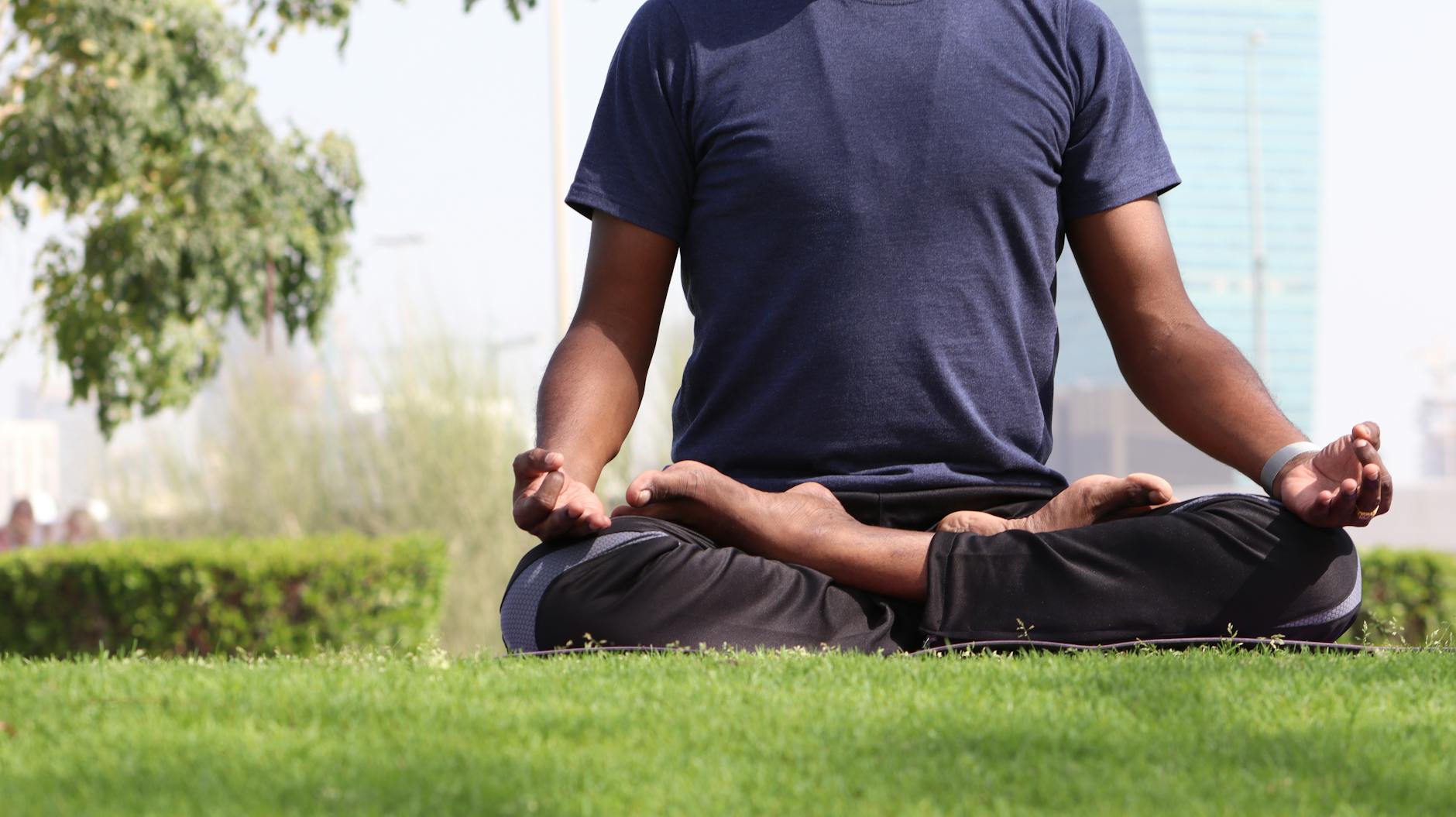 man sitting on grass while doing yoga